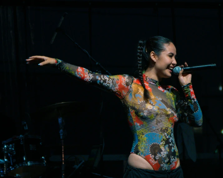 a woman with long ids standing in front of a microphone