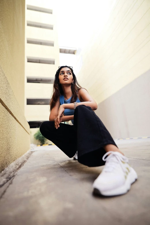 a woman sitting on the ground next to an empty wall