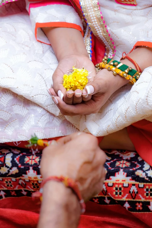 two hands holding yellow flowers and beads