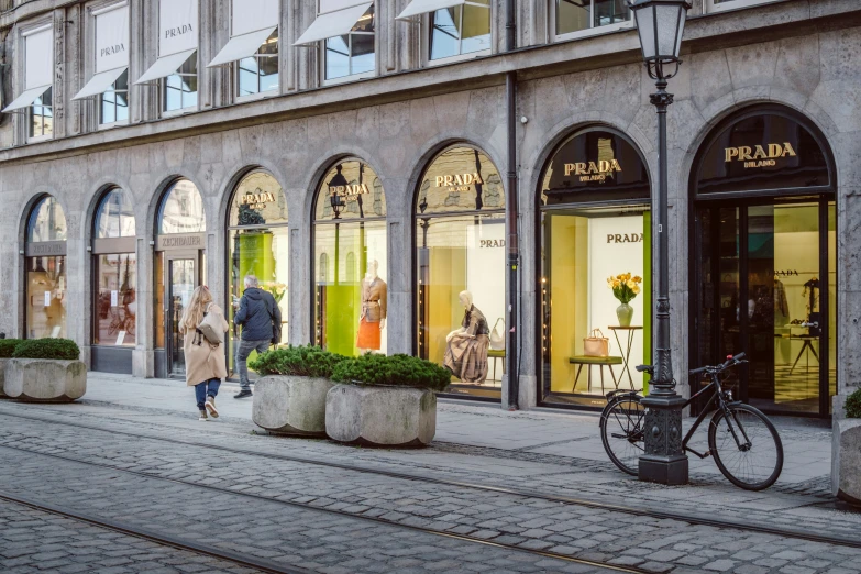 the people are walking down the street in front of some shops