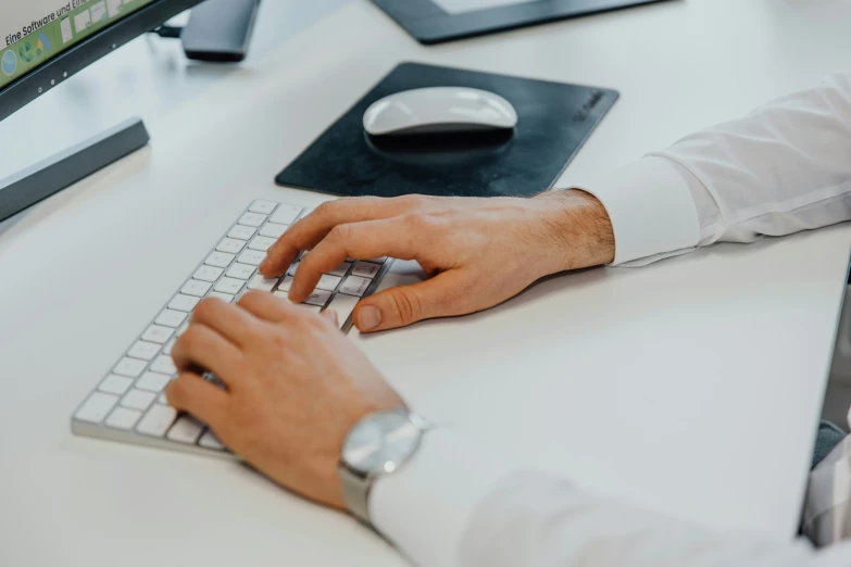 a person using a white computer keyboard on a desk