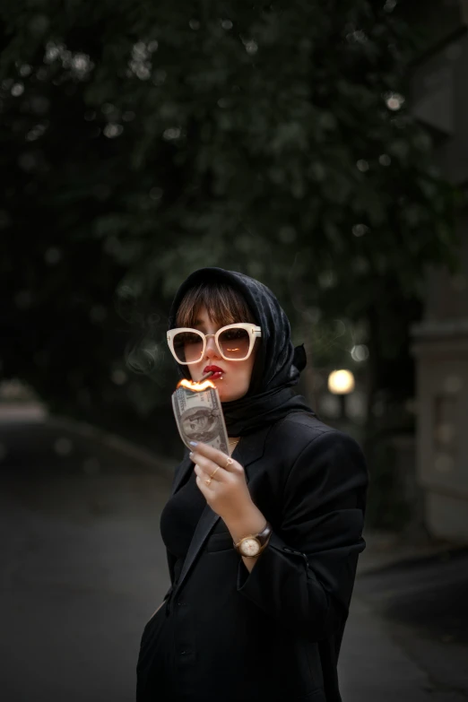 a woman in glasses and a hood looks at her cell phone