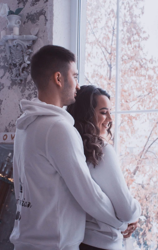 a man and woman smiling by a window together