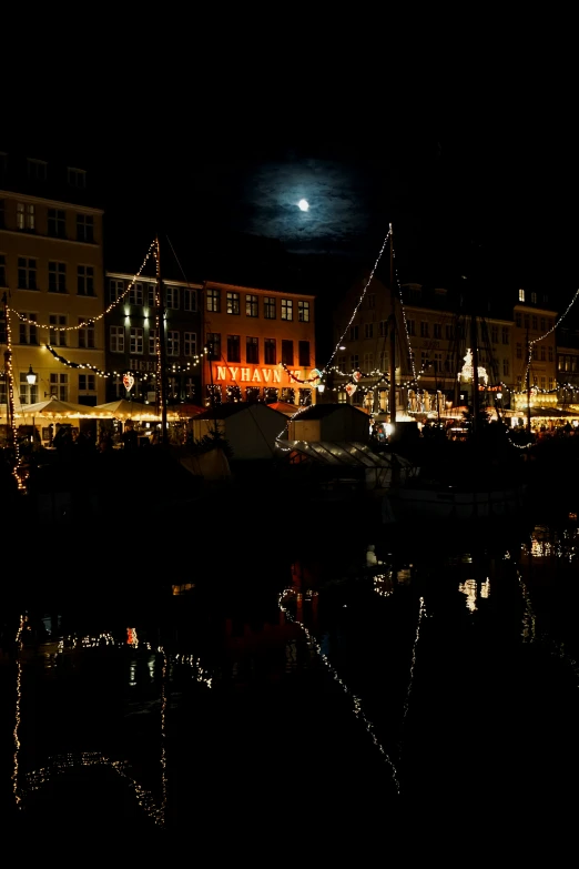 nighttime scene with boats in front of building and city lights