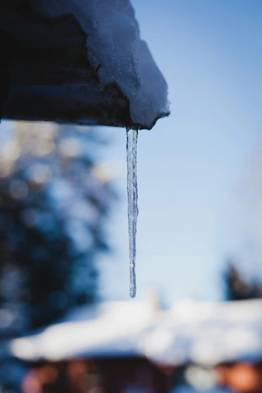 a long ice - covered icicle hanging from a gutter pipe