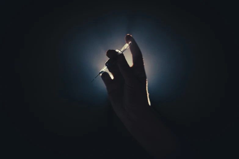 hand holding lit up cigarette against dark background