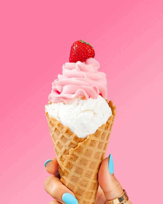 someone holding up an ice cream cone with frosting and a strawberry on top