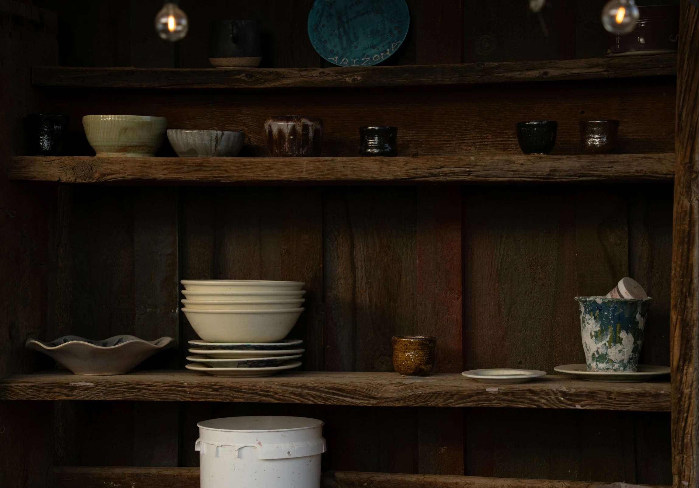 many dishes on a book shelf in the dark