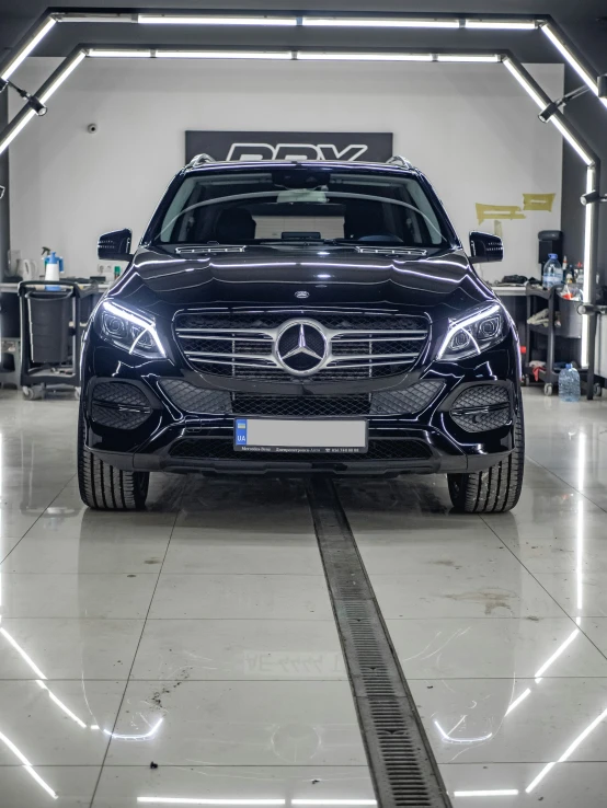 a black mercedes car is parked in a garage with its lights on