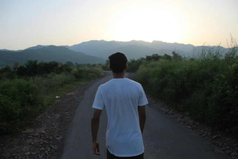 man holding on to a skateboard while walking down a trail