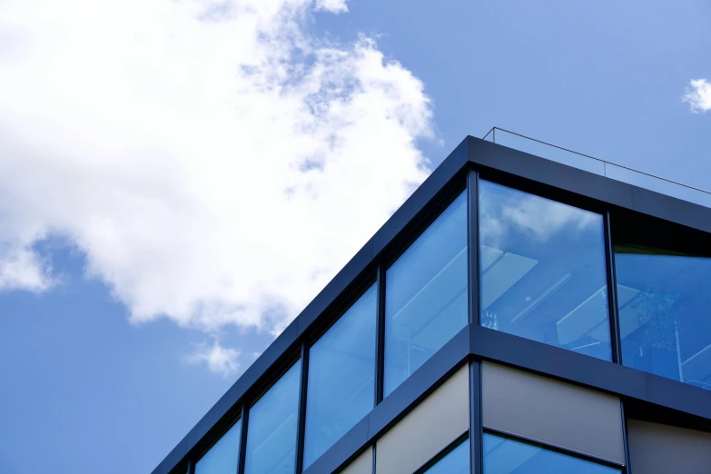 a tall blue building with clouds in the background