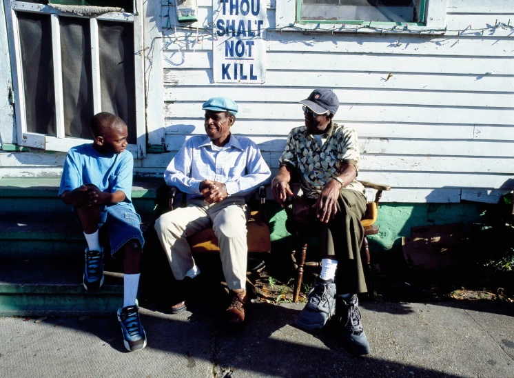 three guys sitting down with one guy holding an infant