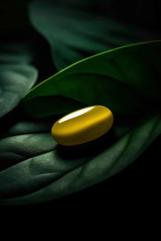 a yellow capsule pill lies on a green leaf