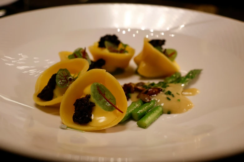a plate is holding ravioli with mushrooms and greens