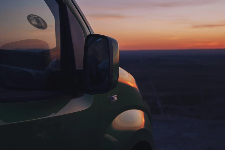 the side of a vehicle with a sunset in the background