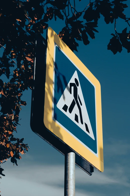 a blue and yellow walk sign sitting on top of a metal pole