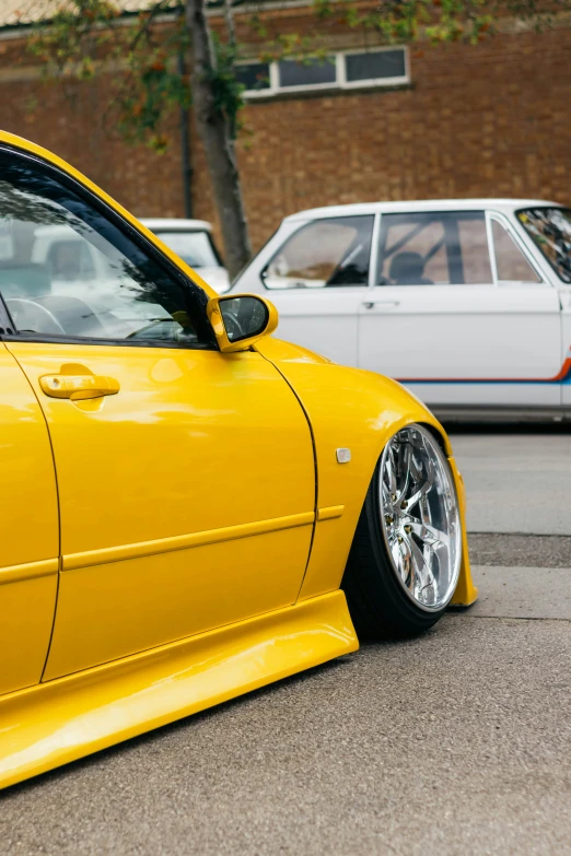 yellow car parked in the street next to two white cars