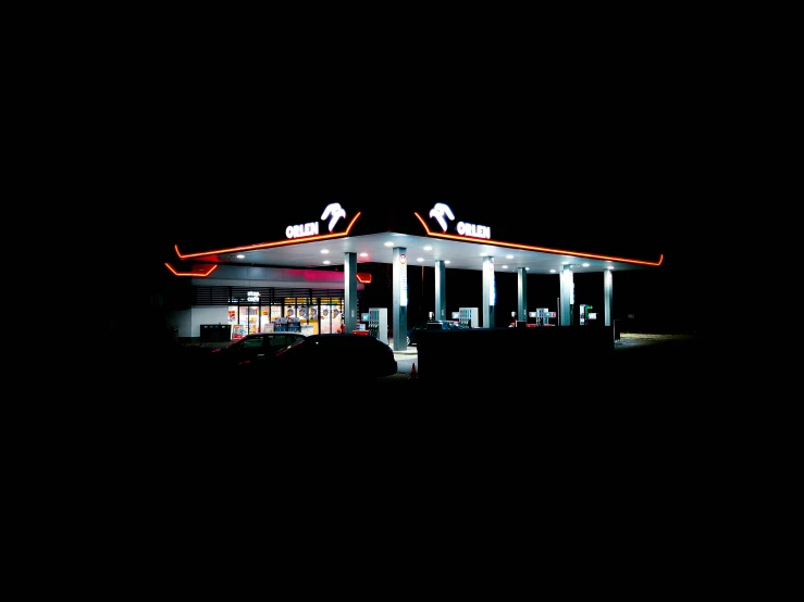 a gas station at night with an orange sign