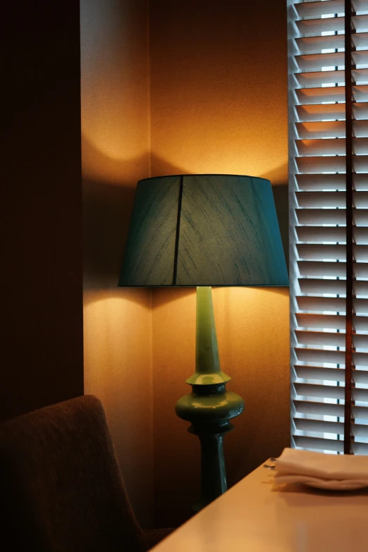 a green lamp in a dark room with a white chair