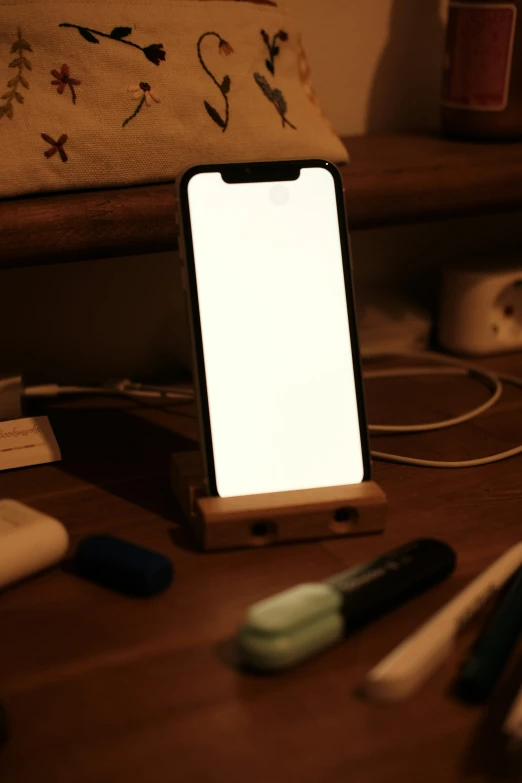 an iphone on a stand beside a table with pen and scissors