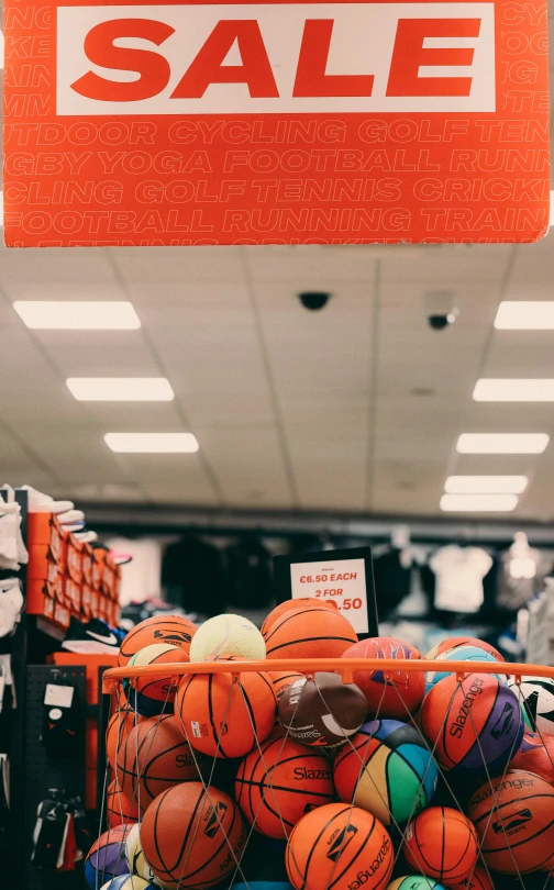 a sale sign with basketballs piled up in the middle of a store