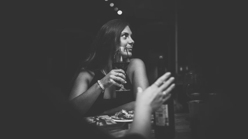 woman in dark room sipping glass of wine