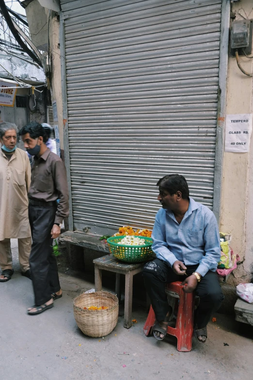 a group of people standing and sitting on the sidewalk