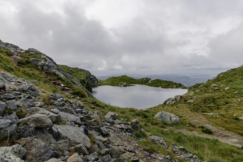 a lake that is on the side of a grass covered hill