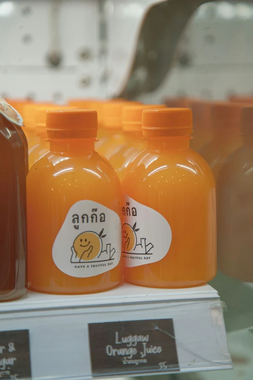 a display case with three bottles filled with orange liquid