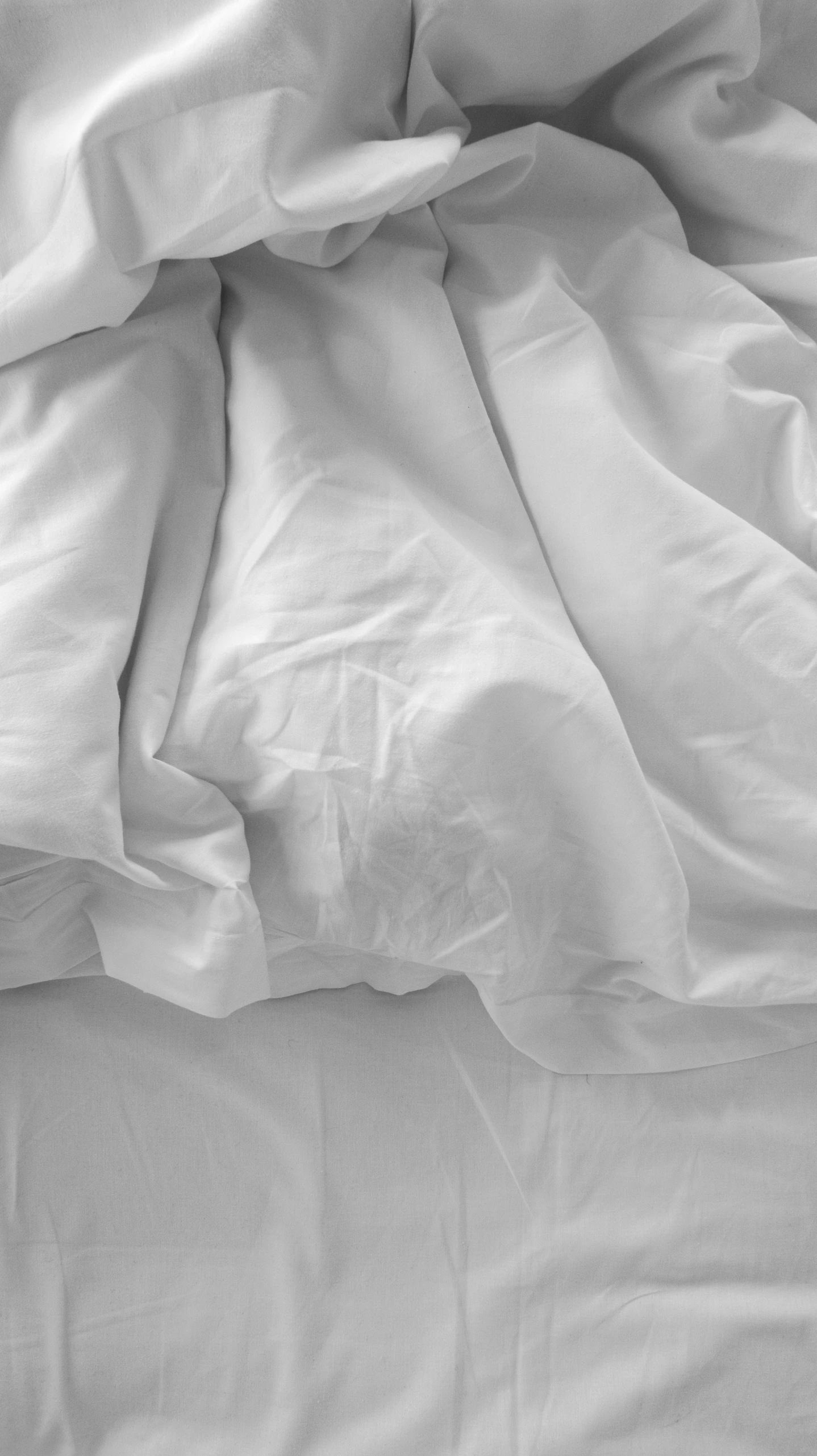 an unmade bed with white sheets and a blanket