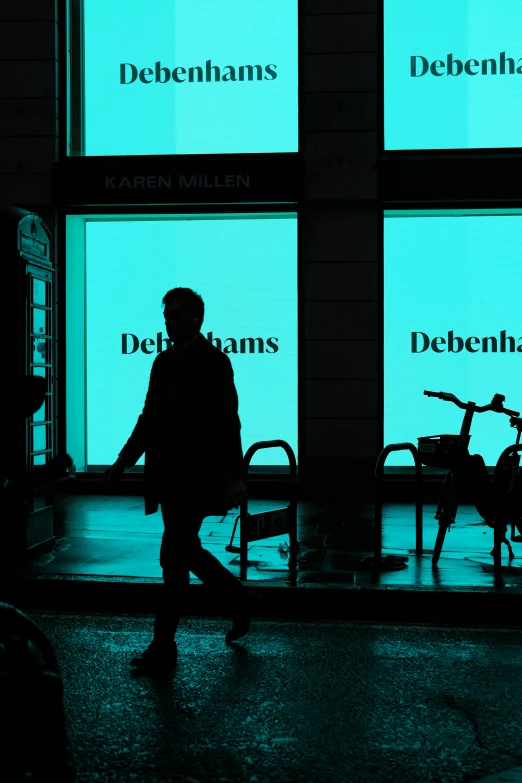 person walking down sidewalk in front of building with bicycles