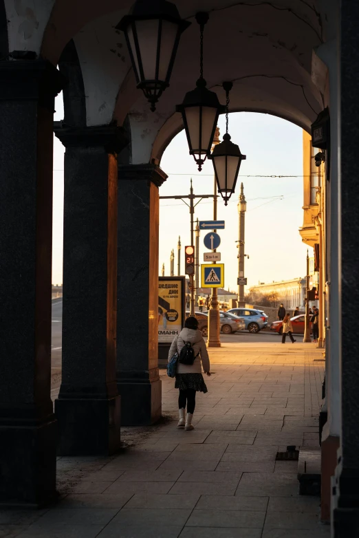 a woman walking down a street in the early afternoon