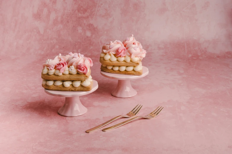 a couple of cake topped with flowers next to two forks