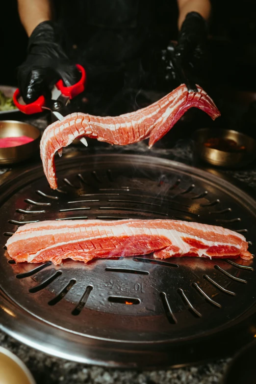 a person is pulling apart cooked bacon from the back of a bbq