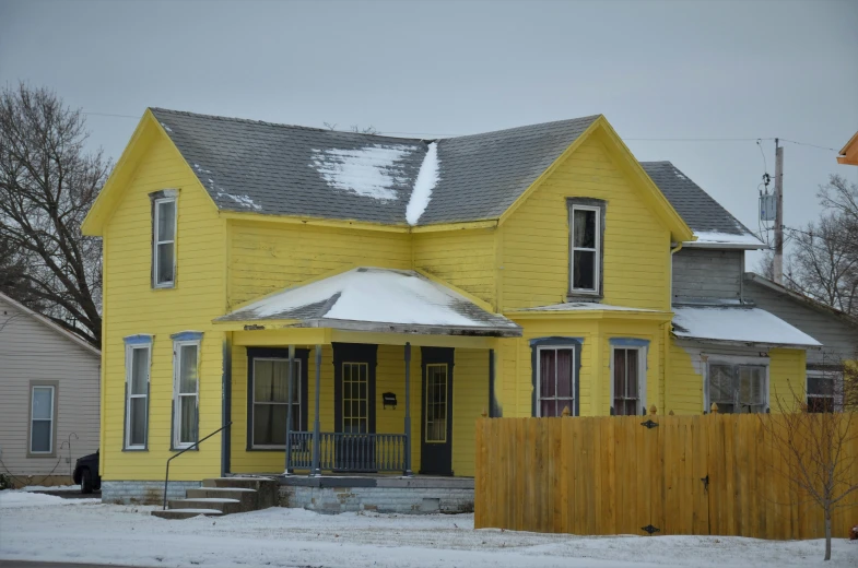 a yellow house has snow on the roof