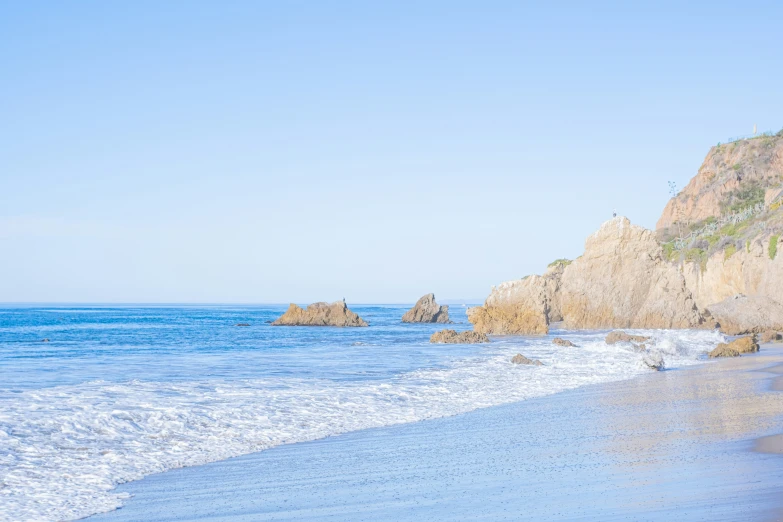 a view of a beach, rocks, and waves coming in