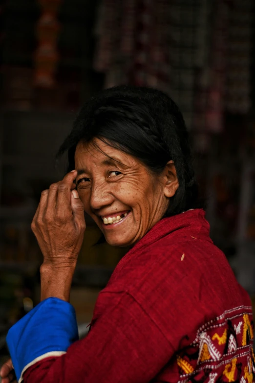 an asian woman wearing a red jacket with hand on a finger