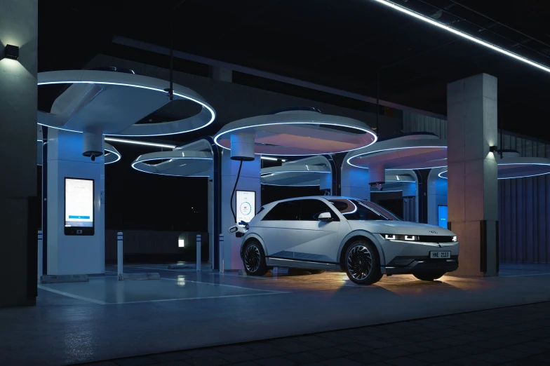 an electric car parked next to a lit entrance at night