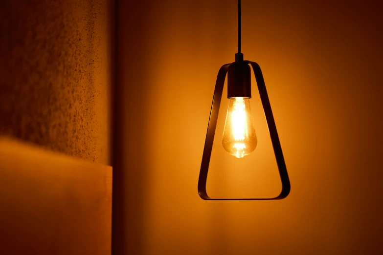 the light bulb hangs on a hanger in an orange tone