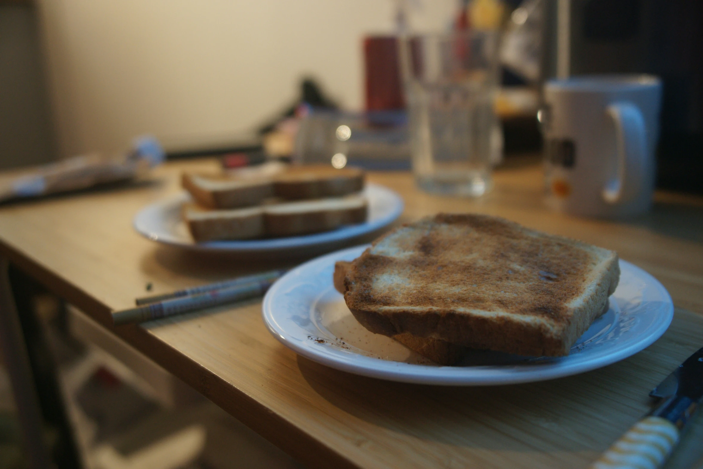 two pieces of toast sit on white plates near coffee cups