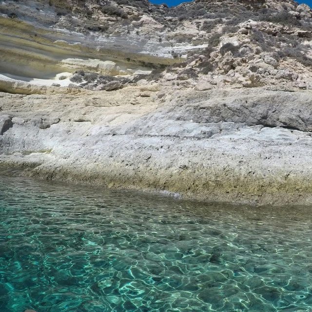 a body of water with a rock face next to it