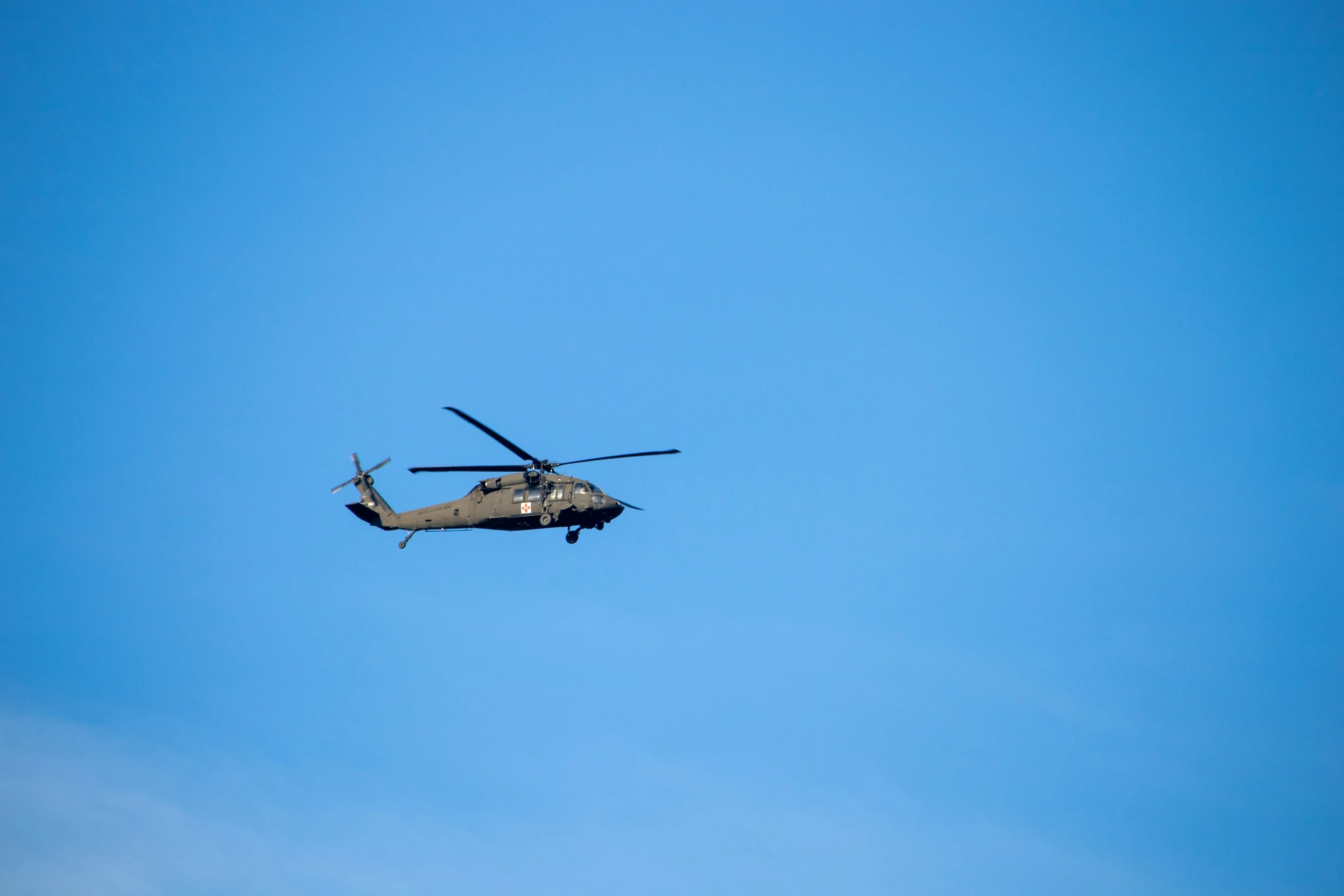 a helicopter flies across the blue sky in a line