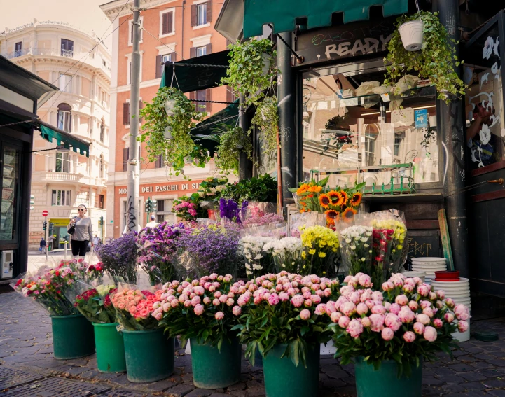 a street side flower shop with flowers on the display