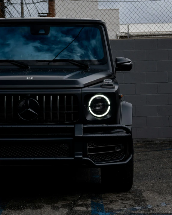 a black car parked in a lot next to a fence