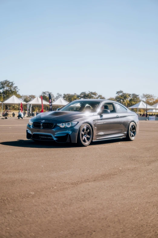 a silver bmw with chrome wheels sits in a field