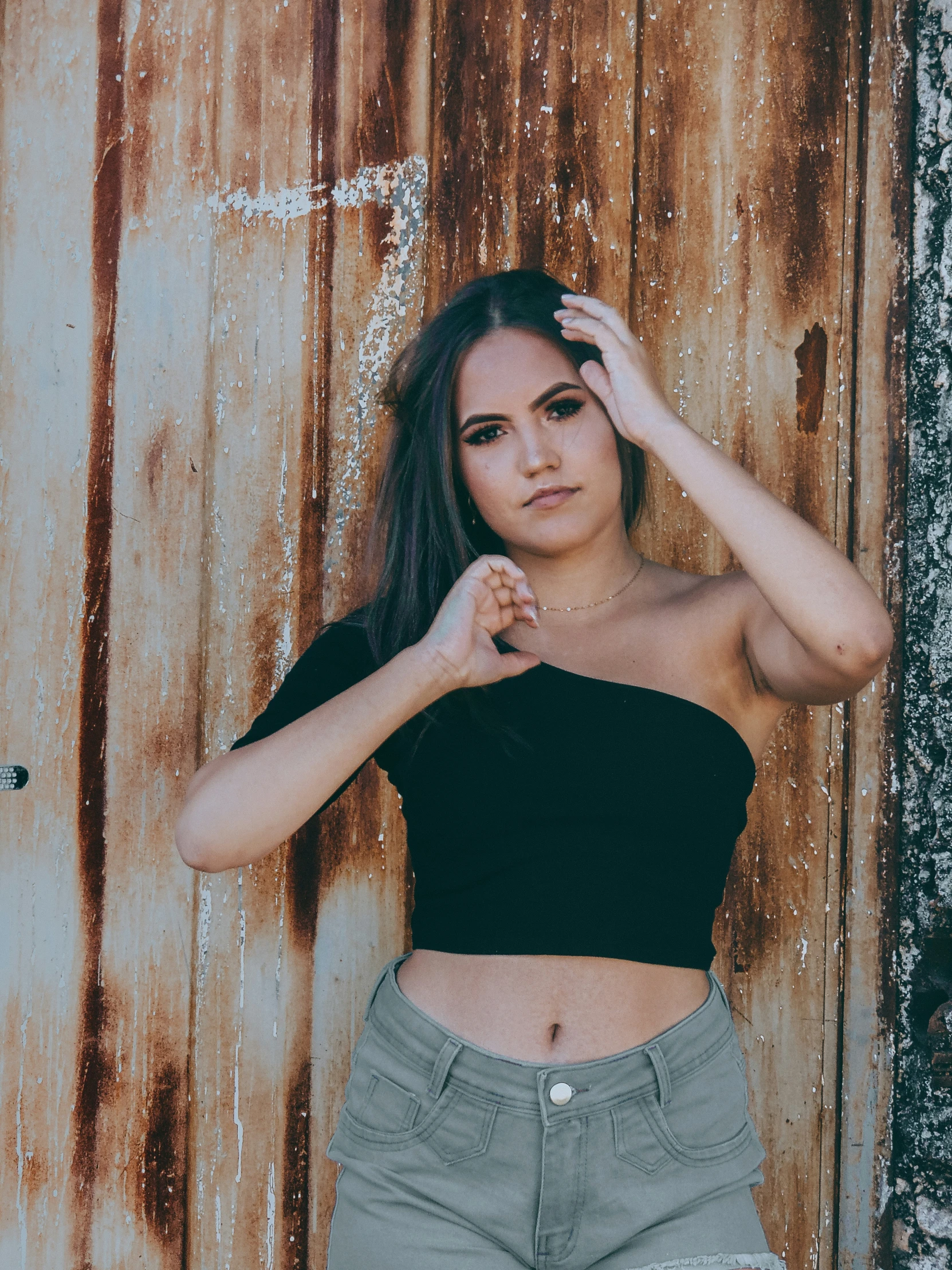 a woman leaning up against a rusty wall