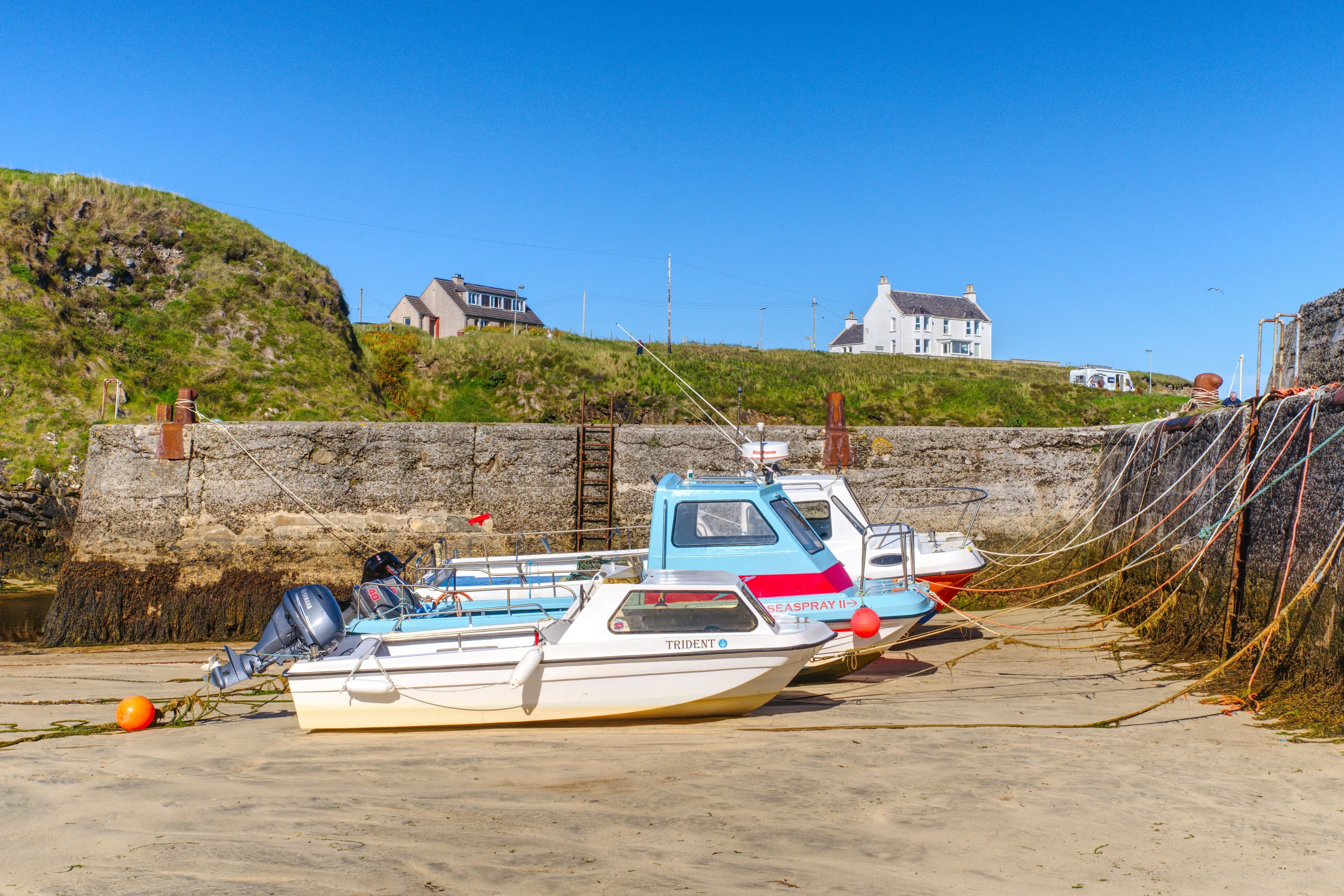 a white and blue boat is parked on sand