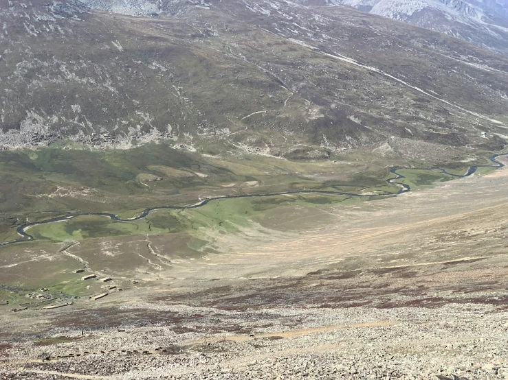 a long, winding road near a hill in the mountains