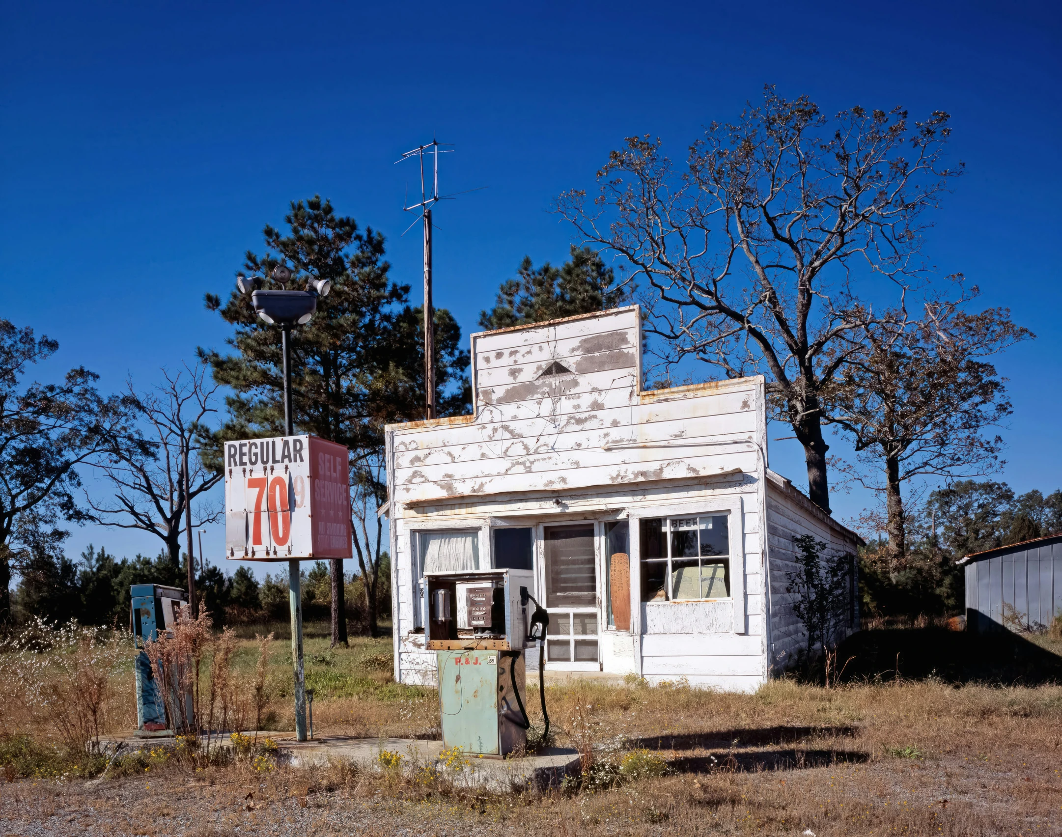 a dilapidated out building sits near two signs