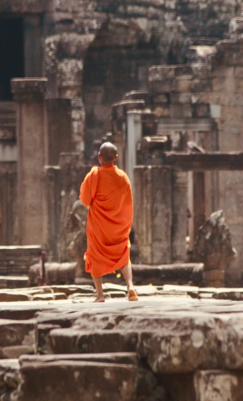 a monk walking down a street in front of ruins